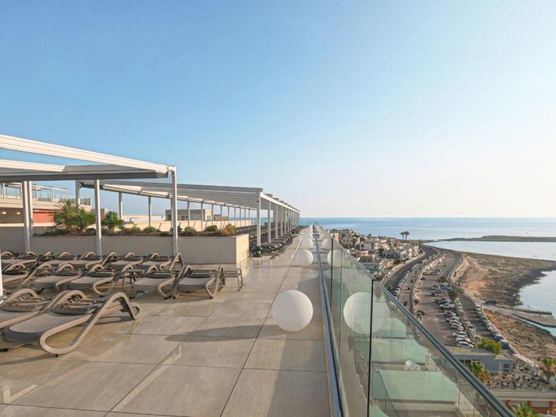 Terrasse avec chaises longues et balustrade en verre avec vue sur la mer par une journée ensoleillée