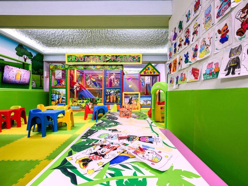 Salle de jeux colorée pour enfants avec décorations murales et jouets dans un hôtel.
