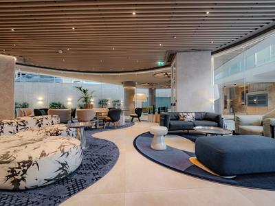 Hall d'hôtel moderne avec sièges confortables, tapis et couleurs sobres.