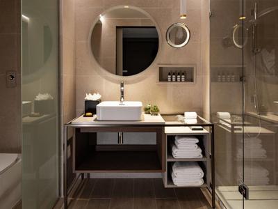 Salle de bain moderne avec lavabo, miroir rond et douche en verre.