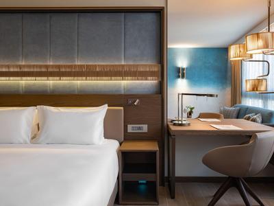 Chambre d'hôtel moderne avec lit double, bureau et éclairage élégant.