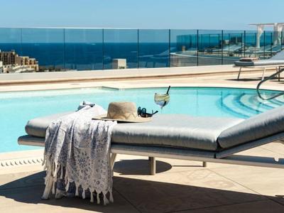 Chaise longue près de la piscine avec serviette, chapeau et vin avec vue sur la mer sur la terrasse de l'hôtel.