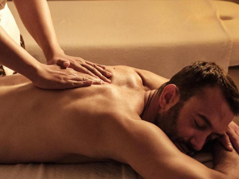 Homme recevant un massage du dos relaxant sur une table de massage avec lumière chaude.
