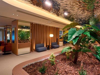 Modern hotel lobby with plants, seating areas, and warm ambiance.