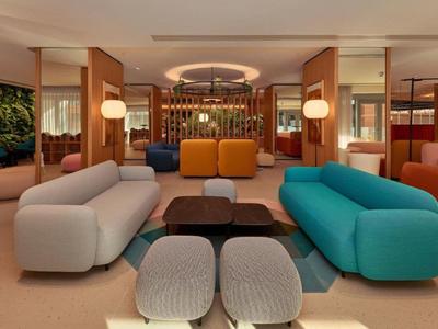 Espace lounge d'hôtel moderne avec canapés colorés et éclairage élégant.