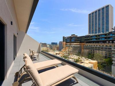 Balcon moderne avec chaises longues et vue sur des immeubles sous un ciel dégagé.