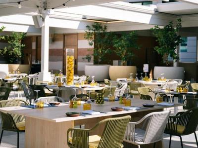 Terrasse de restaurant bien éclairée avec des tables dressées et des plantes.