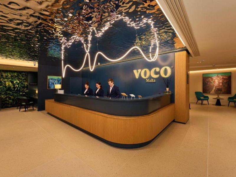 Réception d'hôtel moderne avec comptoir incurvé et installation décorative au plafond.