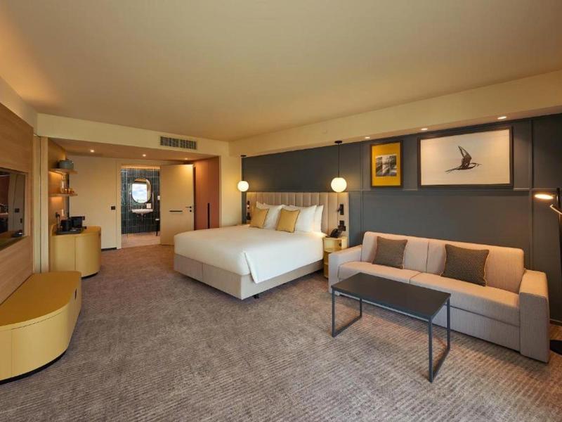 Chambre d'hôtel moderne avec un grand lit et un canapé confortable.