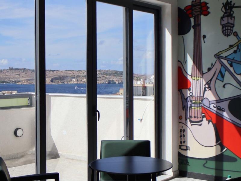 Modern interior with chairs, round table, and view of balcony and sea.