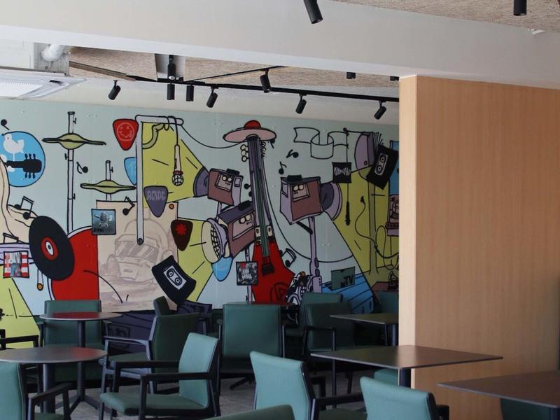 Modern café interior with colorful mural and several tables and chairs.