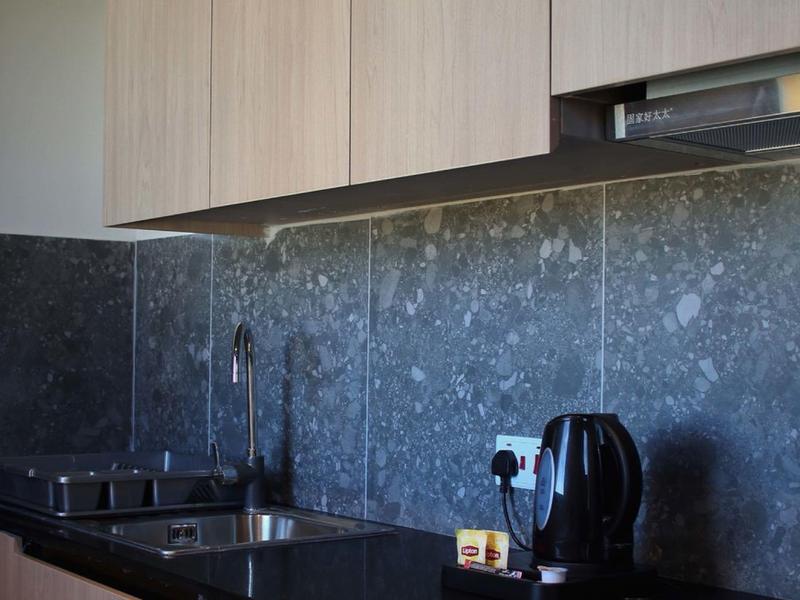 Modern kitchen countertop with stove, kettle, and wooden cabinets in hotel kitchen.