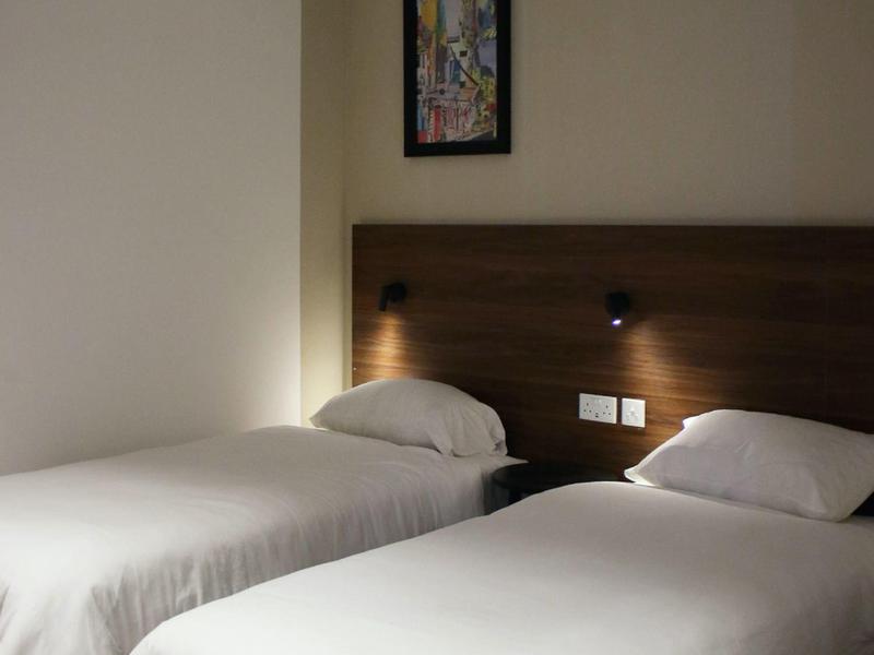 Simple hotel room with two single beds, white bedding, and an air conditioner above the headboard.