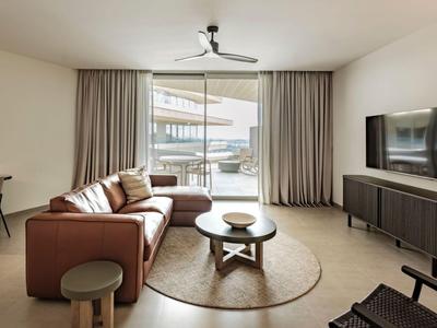 Nowoczesny salon z brązową sofą, okrągłymi stolikami kawowymi i telewizorem na ścianie.