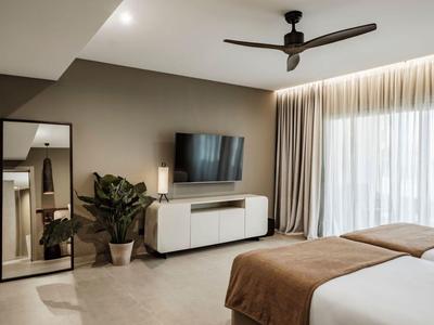 Nowoczesny pokój hotelowy z podwójnym łóżkiem, telewizorem, lampą podłogową i dużym lustrem.