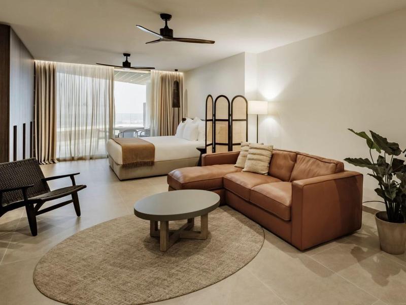 Nowocześnie urządzone pokoje hotelowe z łóżkiem, sofą, fotelami i dużym oknem.