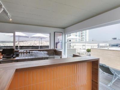 Bar dell'hotel moderno con ampia vista sulla città e sulle montagne, design aperto in legno e vetro.