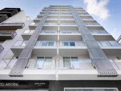 Vista della facciata di un moderno hotel multipiano con balconi e colori chiari.