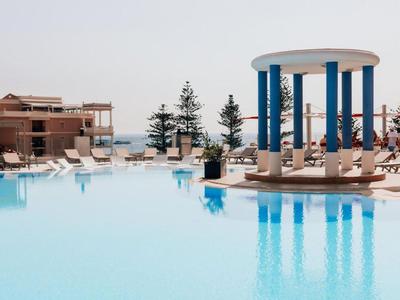 Piscina all'aperto moderna con struttura a colonne blu e bianche e sedie a sdraio vicino al mare