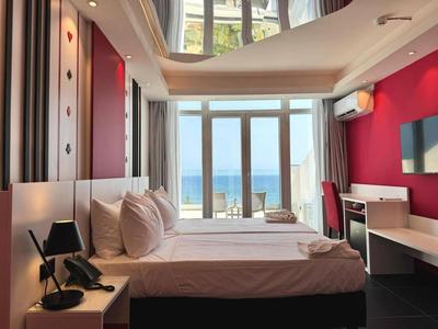 Camera d'hotel moderna con vista mare, letto matrimoniale, scrivania e balcone.