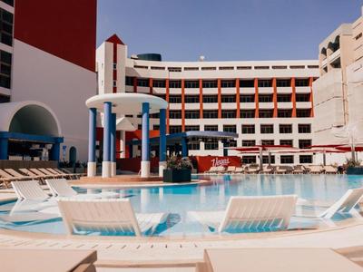 Grande piscina dell'hotel con lettini e colonne sotto un cielo limpido.
