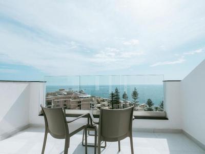 Terrazza con tre sedie e un piccolo tavolo con vista sul mare e sulla skyline della città.