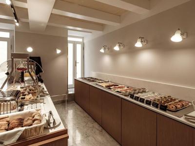 Una stanza per la colazione luminosa con varie paste su lunghi banconi e pareti illuminate.