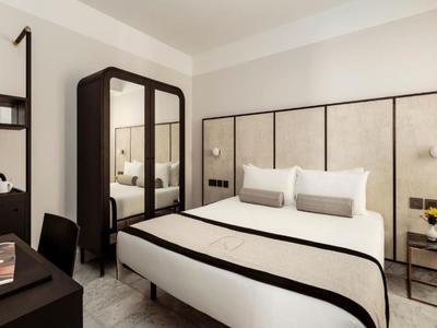 Camera d'hotel moderna con letto matrimoniale, tavolo da trucco e arredamento minimalista.