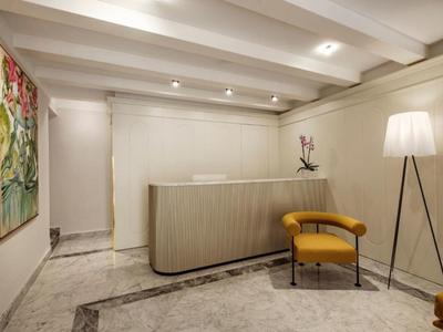 Area reception moderna con bancone elegante, poltrona gialla e lampada da terra con luce calda.