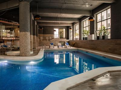Innenpool mit blauem Wasser und Lounge-Bereich in einem modernen Hotel