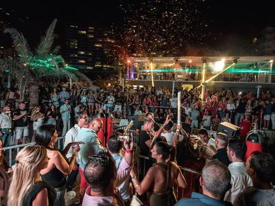 Große Menschenmenge feiert bei Nacht auf einer beleuchteten Open-Air-Party mit Konfetti