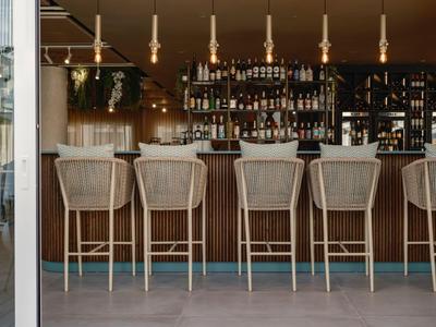 Moderner Hotelbarbereich mit hohen Stühlen und einer großen Auswahl an Spirituosen im Hintergrund.