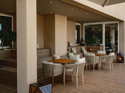 Terrasse mit Tischen und Stühlen neben einem Glasfenster und Stufen.