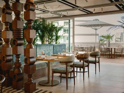 Gemütlicher Innenbereich eines Hotels mit Holzmöbeln und Blick auf eine Terrasse mit Sonnenschirmen.