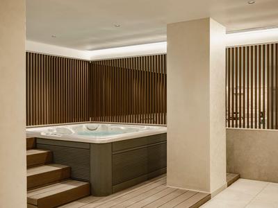 Moderner Whirlpool in einem eleganten Spa-Bereich mit Holzverkleidung und heller Beleuchtung