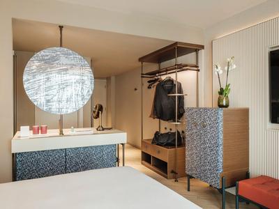 Modernes Hotelzimmer mit Bett, großem Spiegel, Garderobe und stilvollen Möbeln.