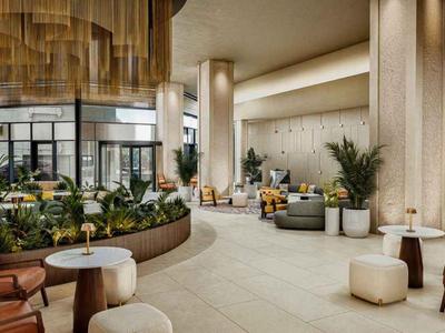 Moderner Hotellobby-Bereich mit bequemen Sitzgelegenheiten und grünen Pflanzen in warmem Licht.