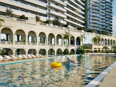 Luxushotel mit großem Pool, Sonnenliegen und umliegenden Palmen unter klarem Himmel.