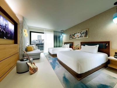 Modernes Hotelzimmer mit zwei Queensize-Betten, großem Fenster und zeitgenössischer Einrichtung.