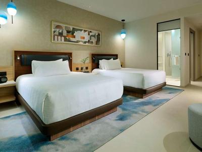 Modern eingerichtetes Hotelzimmer mit zwei großen Betten und stilvollen Lampen.