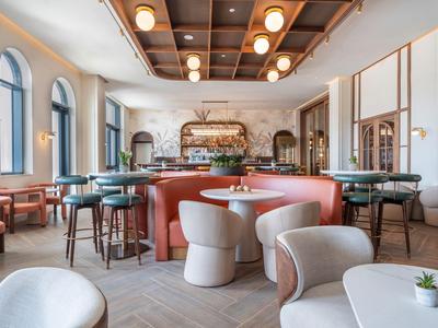 Elegante hotelbar met moderne stoelen, ronde tafels en warme plafondverlichting.