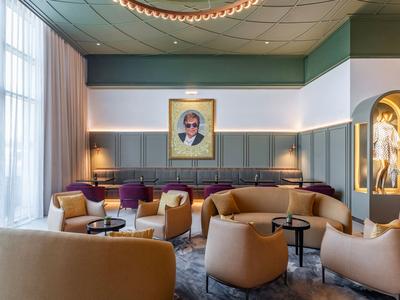 Elegante hotel-loungeset met beige fauteuils, groene bank en groot raam