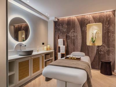 Elegante spa-ruimte met massagetafel, ronde spiegel en zachte verlichting.
