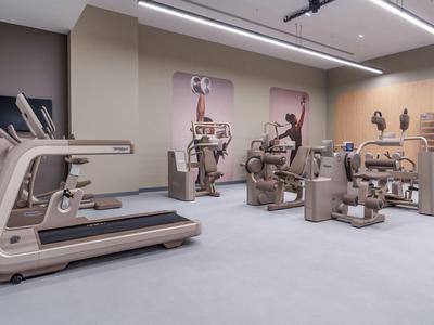 Moderne hotel fitnessruimte met diverse fitnessapparaten en neutrale kleuren.