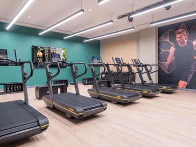 Moderne sportschool met meerdere loopbanden, grote muurschilderingen en helder licht.
