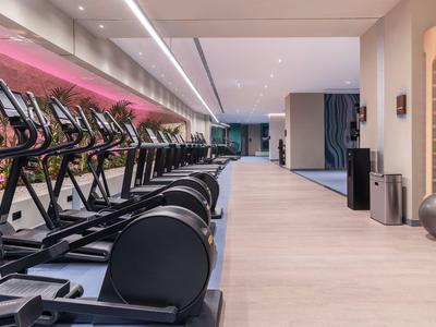 Moderne fitnessruimte met loopbanden, heldere vloer en stijlvolle verlichting in hotel.