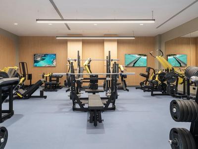 Goed uitgeruste fitnessruimte met krachtapparaten, dumbbells en spiegels in een hotel.