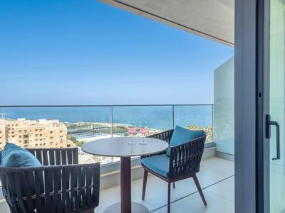 Balkon met twee stoelen en tafel met uitzicht op zee op een zonnige dag.