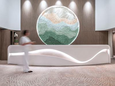 Moderne hotelreceptie met gebogen balie en rond wandkunstwerk in houten lambrisering.