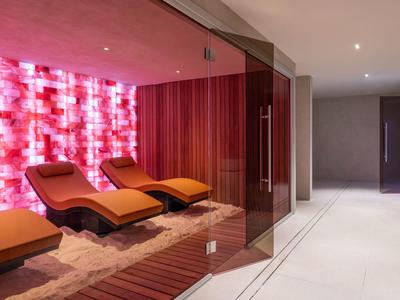 Ontspanningsruimte met oranje ligstoelen en een rode accentmuur in een modern hotel.